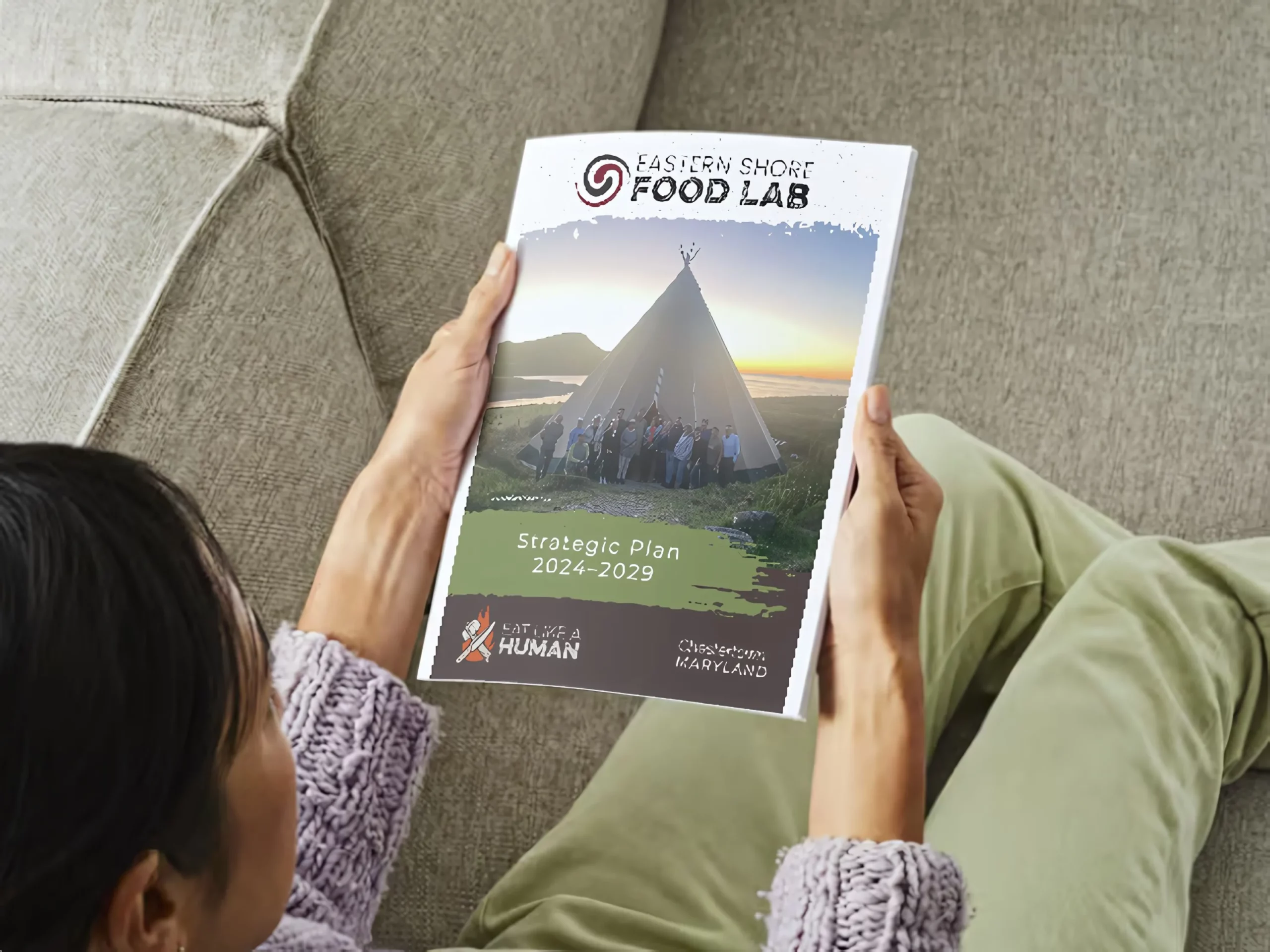 A document held in the outstretched hands of a woman sitting near a coach.